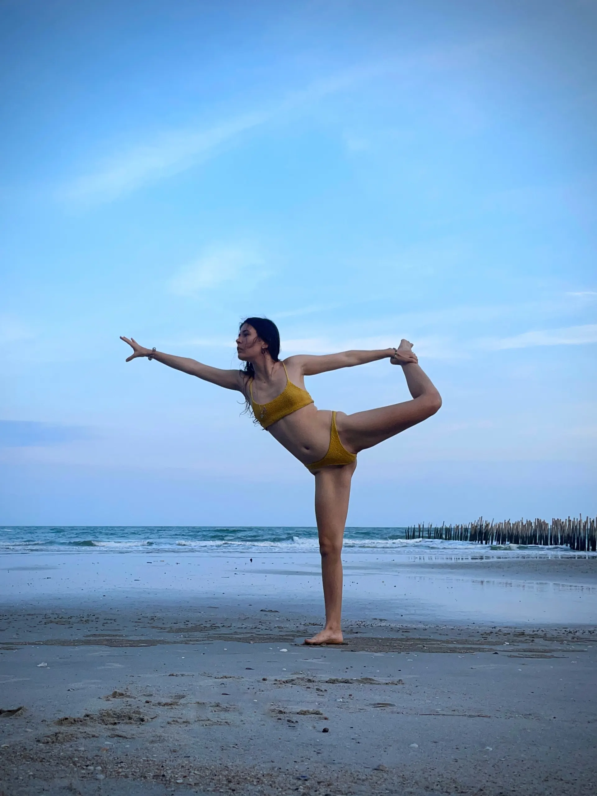 Nana balancing in a yoga pose beside the sea