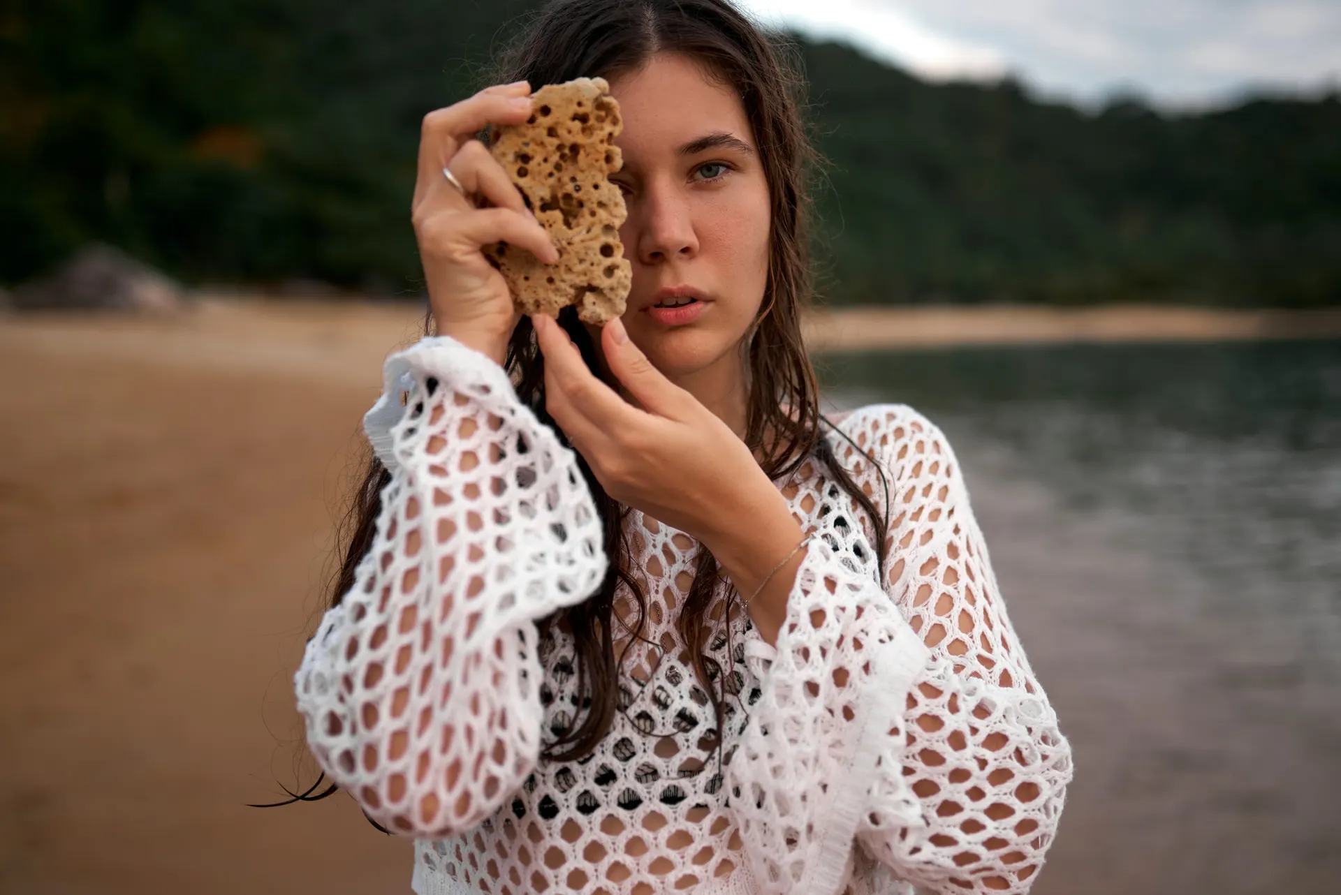 Nana holding a shell beside her face on the beach