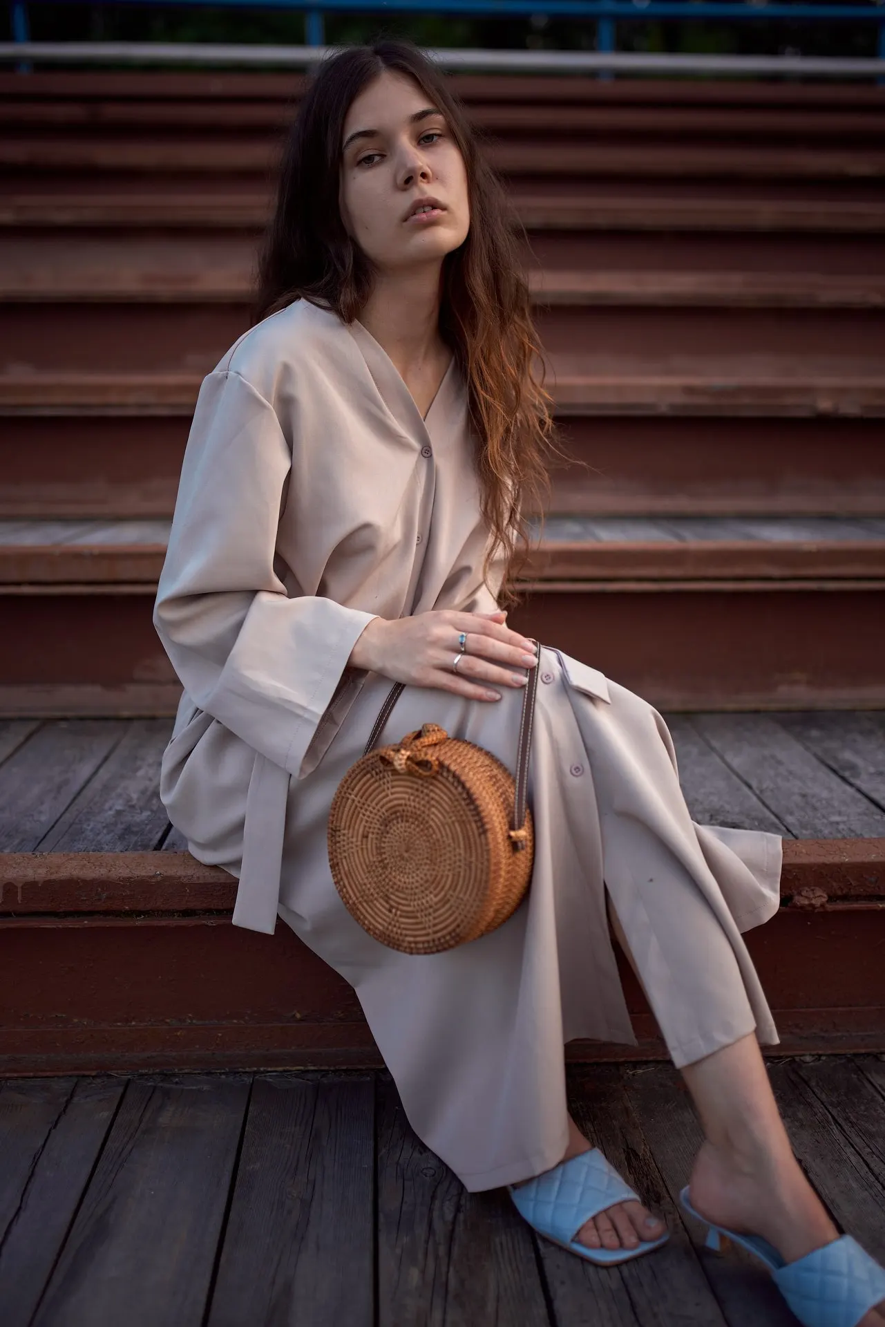 Nana seated on steps with a round woven bag