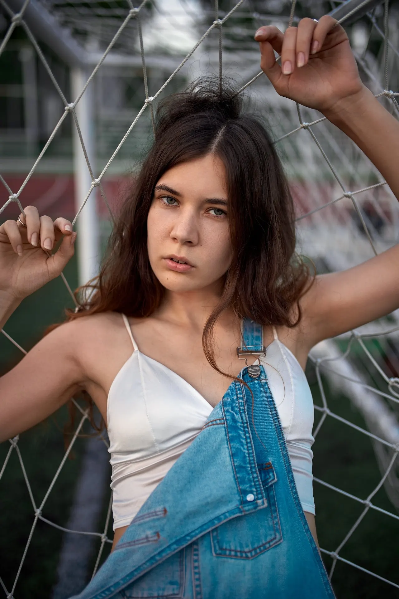 Nana in denim overalls leaning against a football goal
