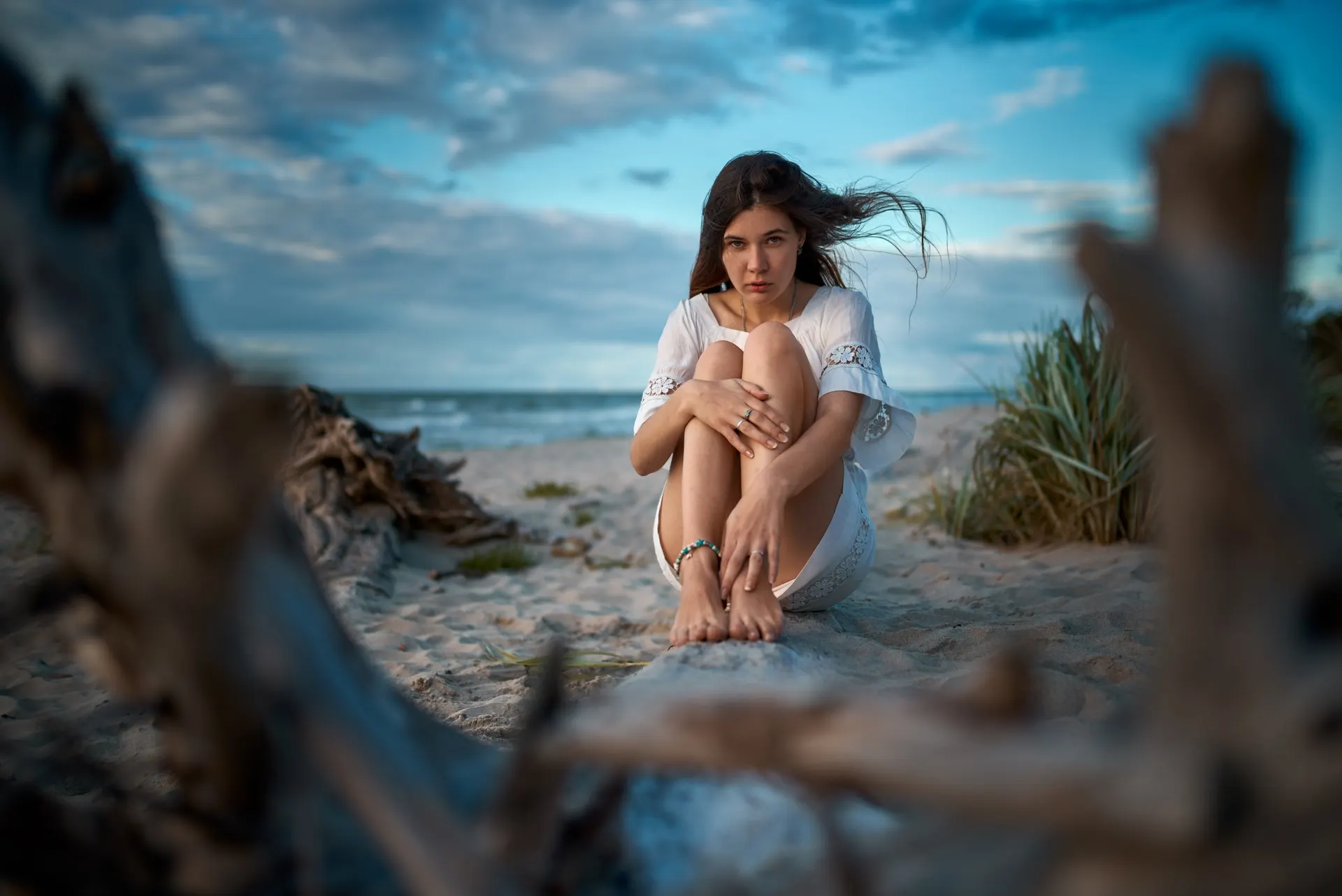 Nana seated on the beach, framed by driftwood