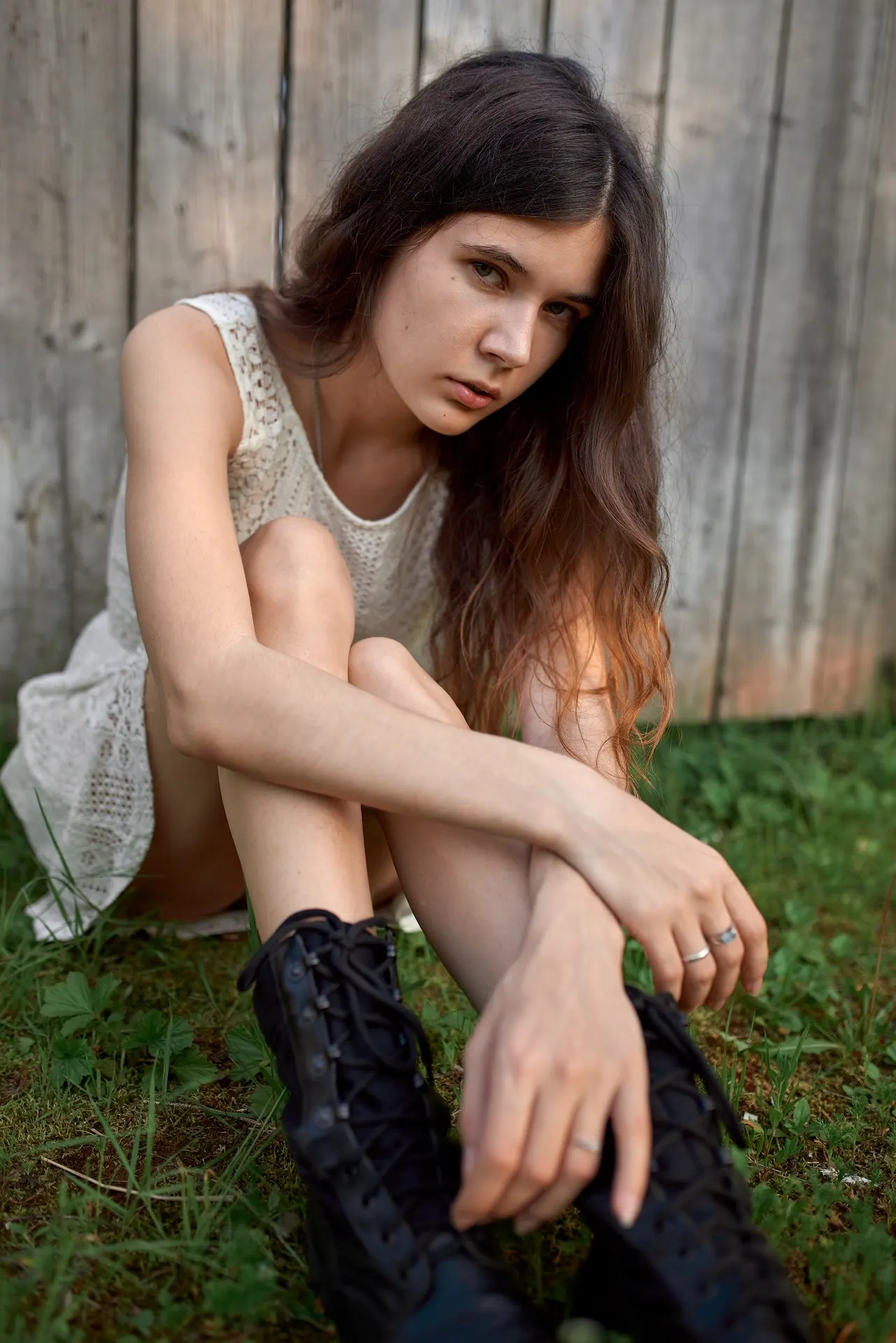 Nana seated beside a wooden fence, resting her arms on her knees