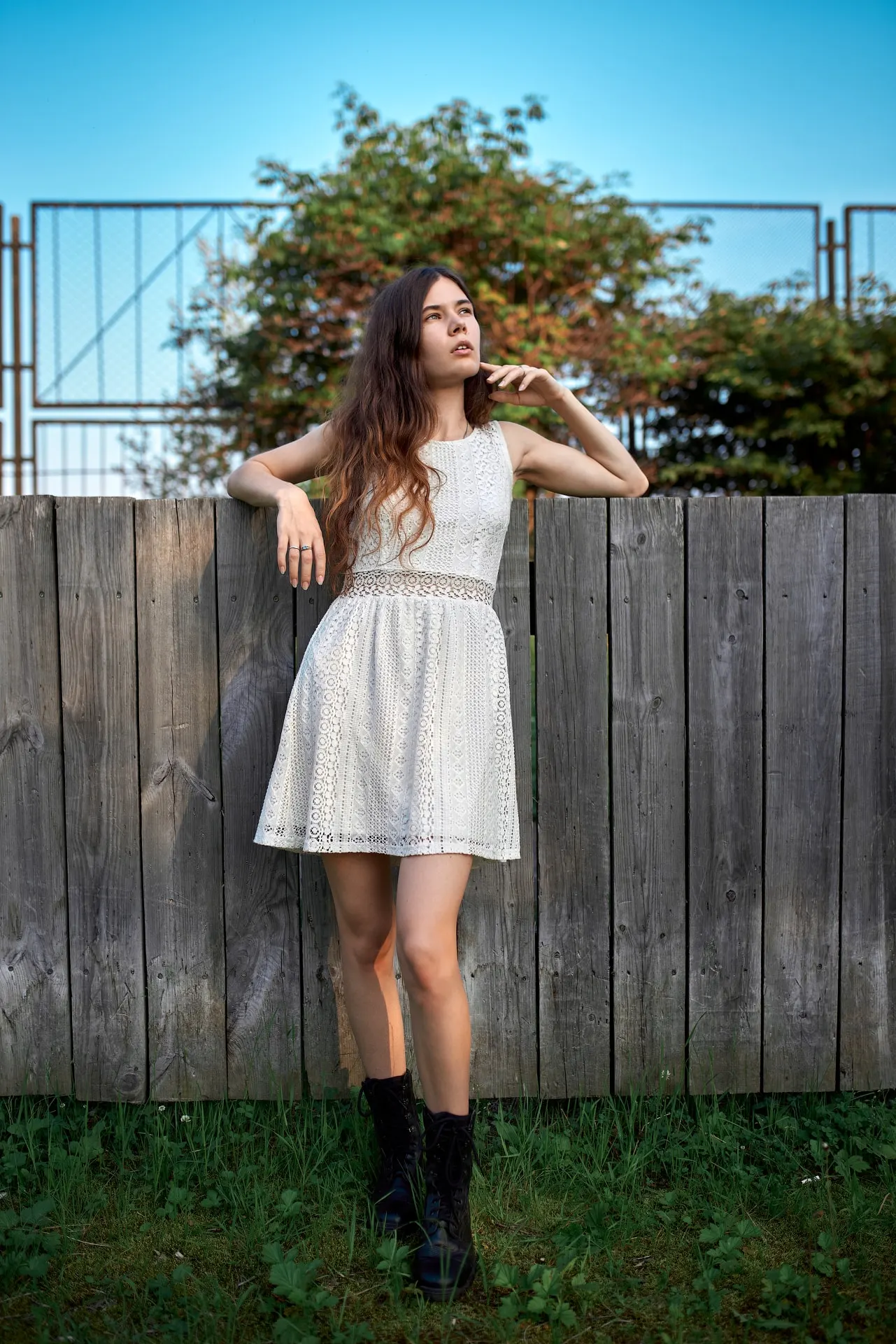 Nana in a white dress standing by a wooden fence