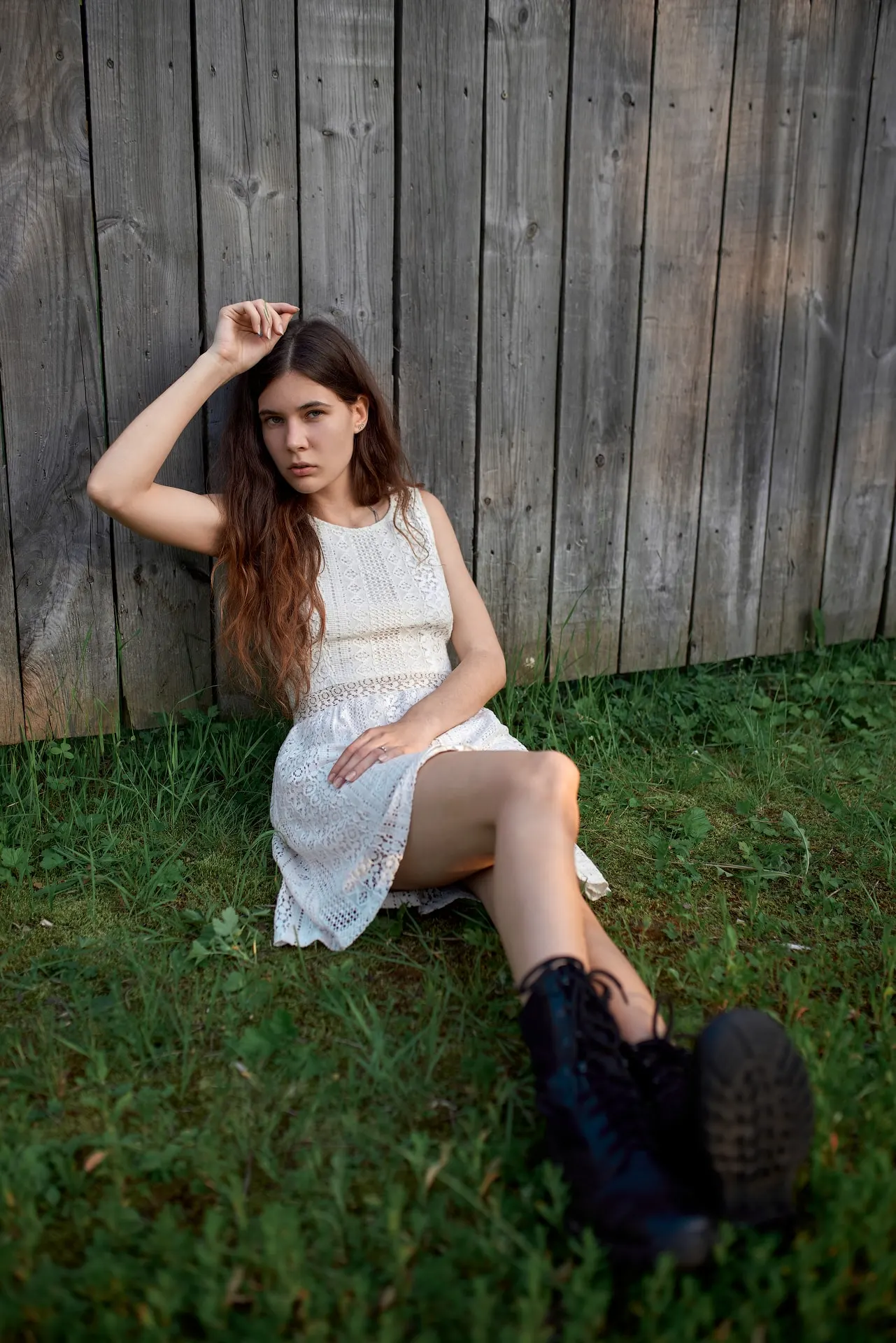 Nana in a light dress seated beside a wooden fence