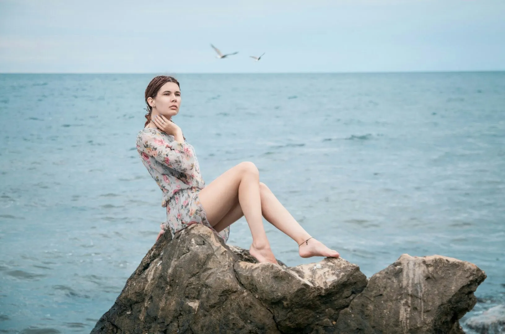 Nana seated on a rock above the sea