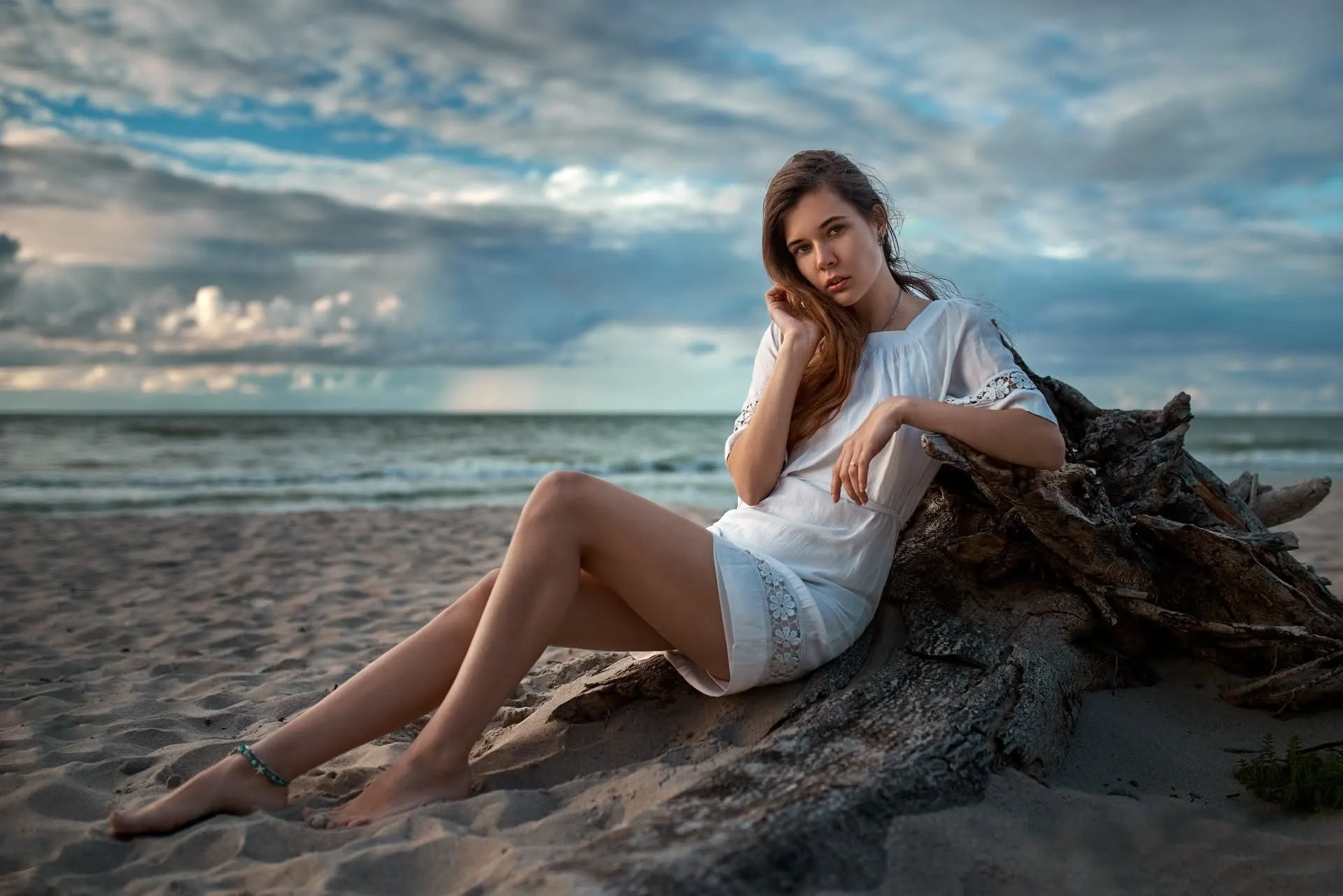 Nana seated beside driftwood at the water's edge
