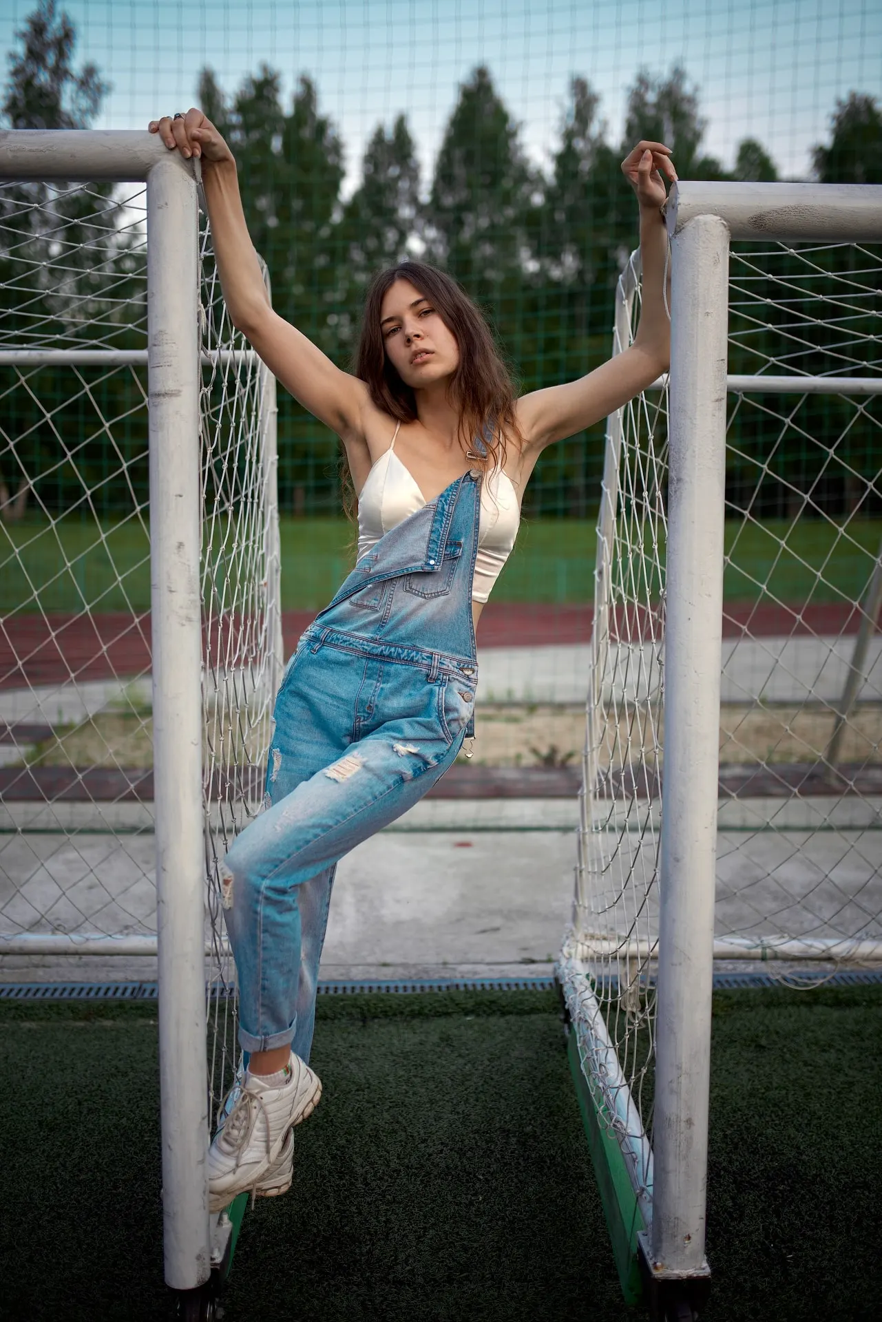 Nana in denim overalls beside a football goal