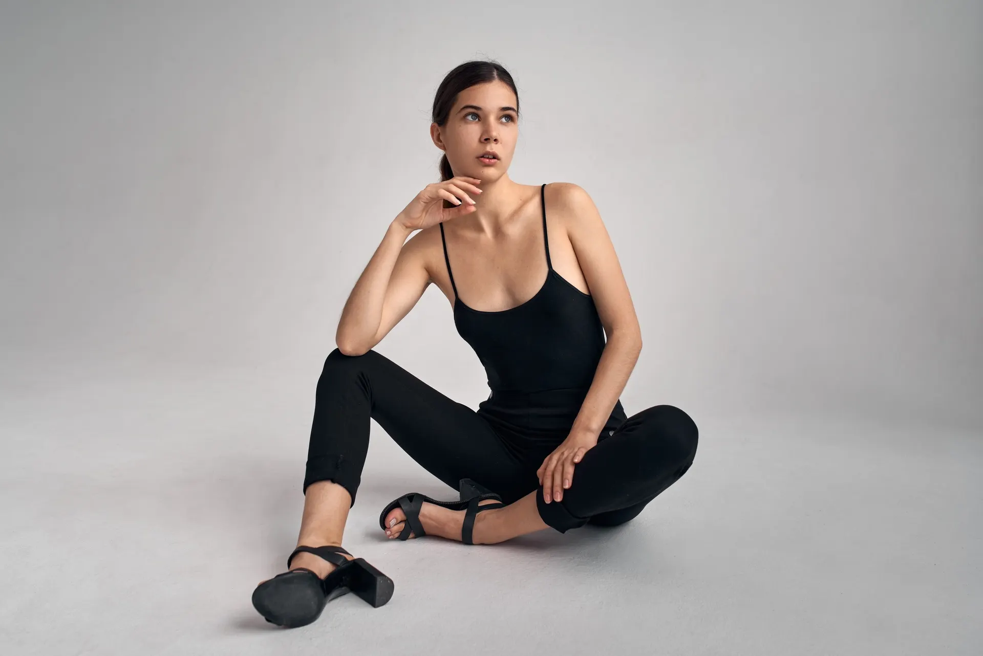 Nana seated in a black outfit against a pale studio backdrop