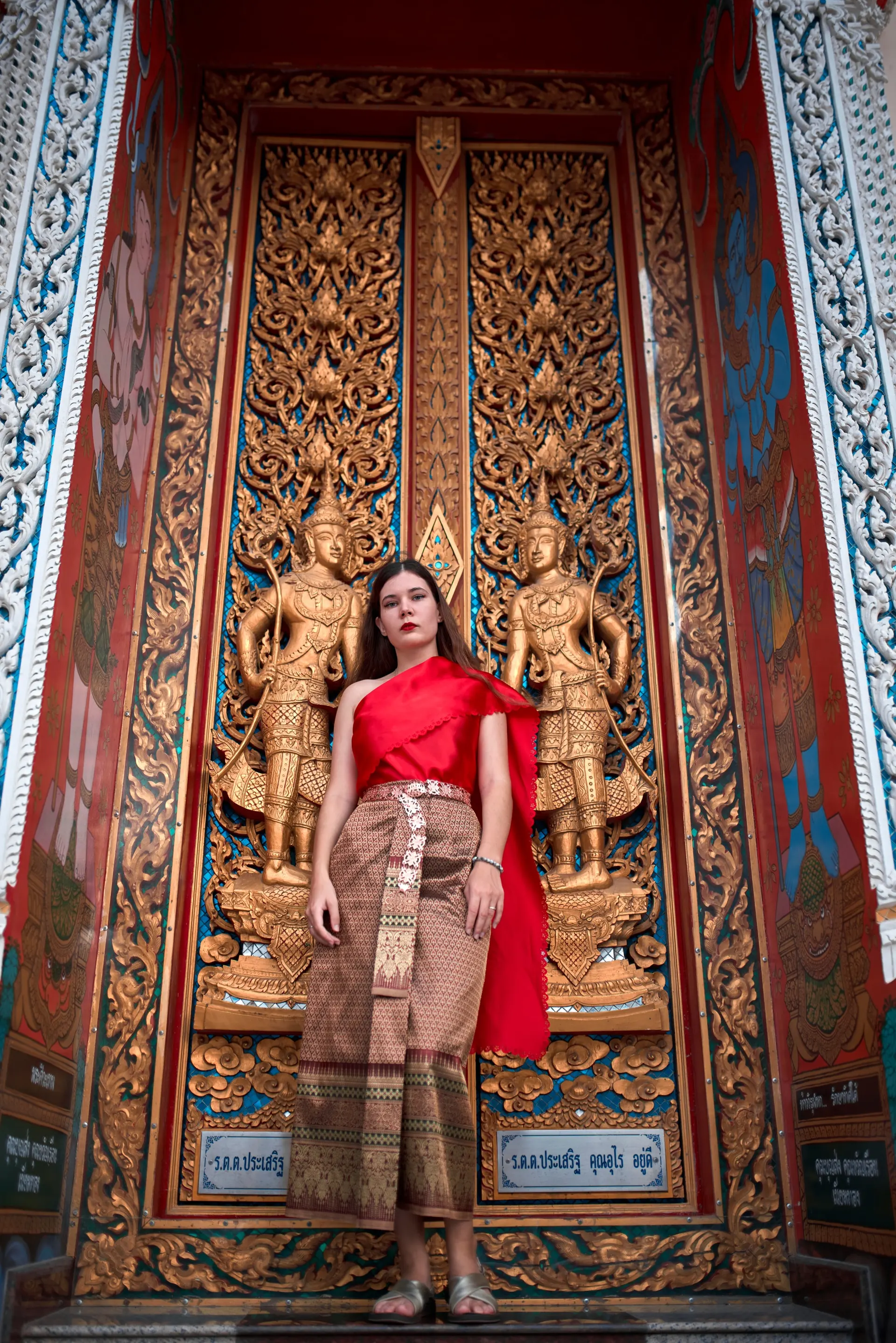 Nana standing between golden guardian figures on a carved temple door